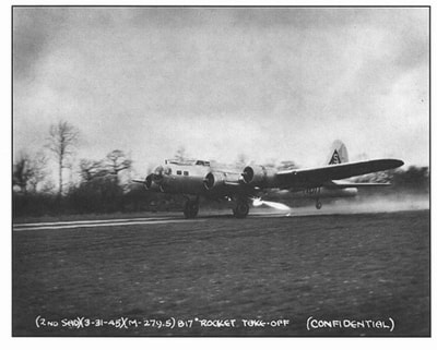 It appeared to be an impossible situation.  The B-17 was intact, save for wing, tail and prop damage. But it was hundreds of yards from the main runway, mired in a mushy barley field on "Gypsy Farm," northeast of Station 131.  Towing it out was deemed impossible, and yet the Fortress was surely salvageable.
It was inadvertently "parked" there on February 4, 1945 by a new, skeleton crew who had been "slow-timing" an engine at night.  What the crew thought were runway lights were actually part of the RAF "DREM" lighting system on poles designed to "funnel" planes into the landing pattern.
Pilots Allen Ferguson and John Schmidt were cleared for landing. And so they did ... in the barley field ... taking with them a wooden chicken coop and a hundred chickens.
The plane came to rest with one of the funnel light poles lodged between No.3 engine and the fuselage. The most serious damage was to the starboard wing panel, and it was replaced before the "rocket assist take-off' on March 31, 1945. (The old wing panel is on display in the Leo Croce Nissen Hut at the Nuthampstead Airfield Museum.) 
The tail fin also was replaced with a reclaimed spare from the 1st Air Division's "2nd Strategic Air Depot" at Abbots Ripton (Alconbury). This explains the "Triangle S" marking of the 401st BG from Deenthorpe, rather than the "Triangle W" from the 398th.
The use of rockets to boost a B-17 aloft was unheard of at the time and exactly how the rocket plan originated is still not clear.  It is thought it might have been the idea of the pilot sent to review the problem- Capt. Richard C. Holub or M/Sgt. Raymond L. Kirkpatrick, who had worked with Capt. Holub previously.  Both were from the 1st Air Division's 2 SAD.
Holub was a skilled pilot specializing in short take-offs and Kirkpatrick, served as co-pilot and "trigger man" with the rockets.
Gen. Doolittle, there to witness the event, asked Holub- "Do you think you can pull this off?"
"I can do it," replied Holub.
And he did.

** The above excerpt is from Allen Ostrom's article in the July 2002 Flak News.
